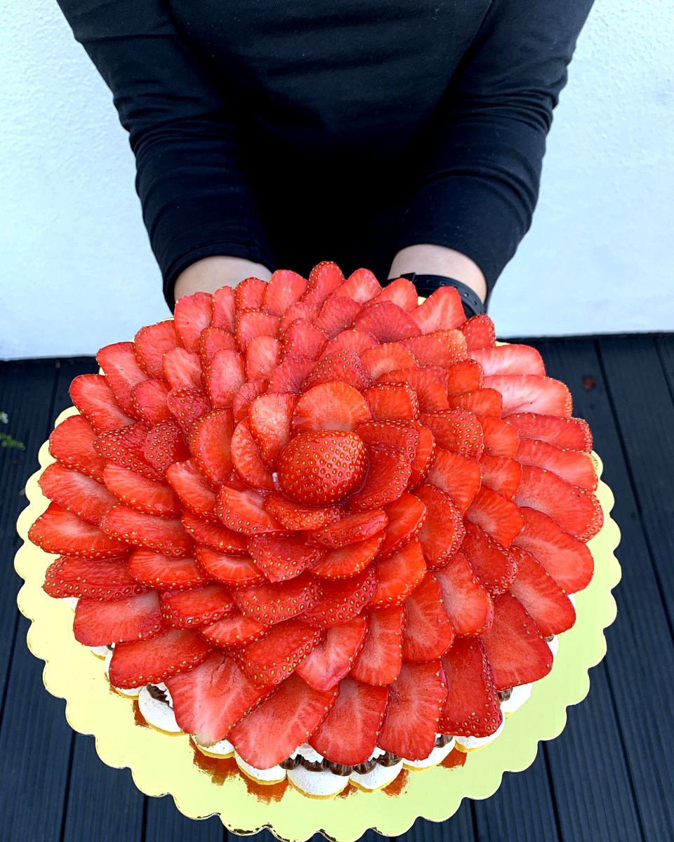 A Cakish pavlova being presented, showing the full layered construction with meringue, filling, cream, and strawberries.
